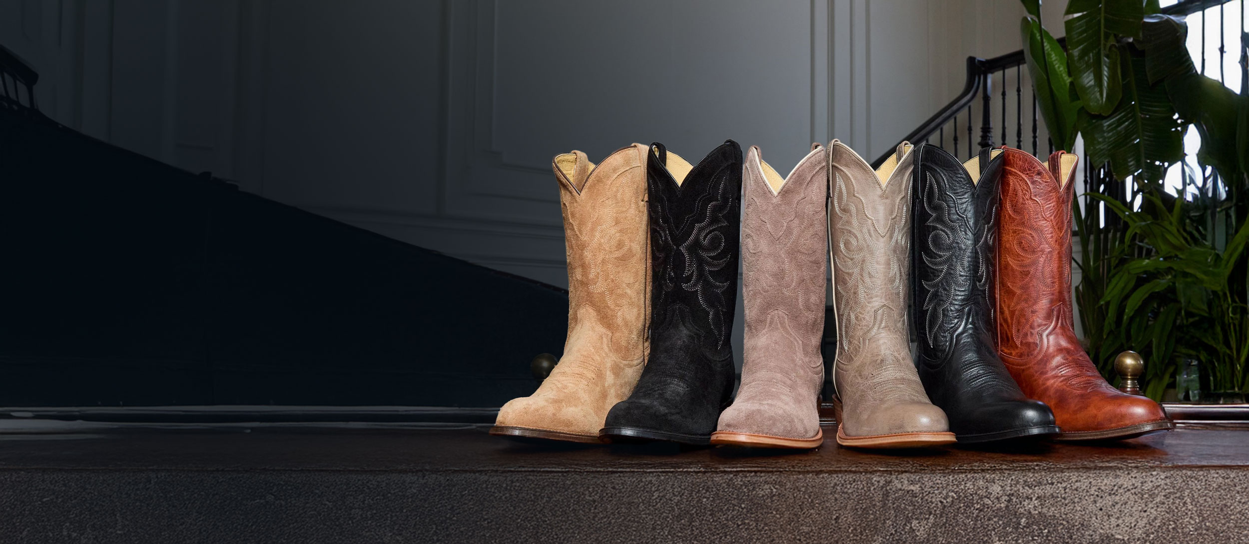 A lineup of the Marco and Plano 12” Western boots in various colors on a coffee table.